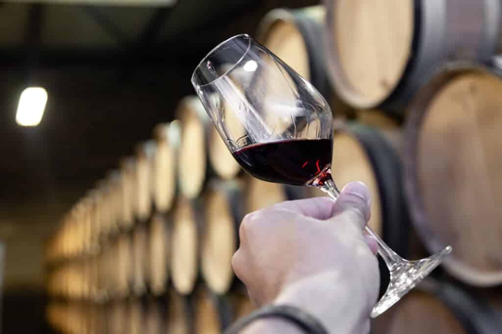 Closeup hand with glass of red wine on background wooden oak bar Scholar of Modern Wine